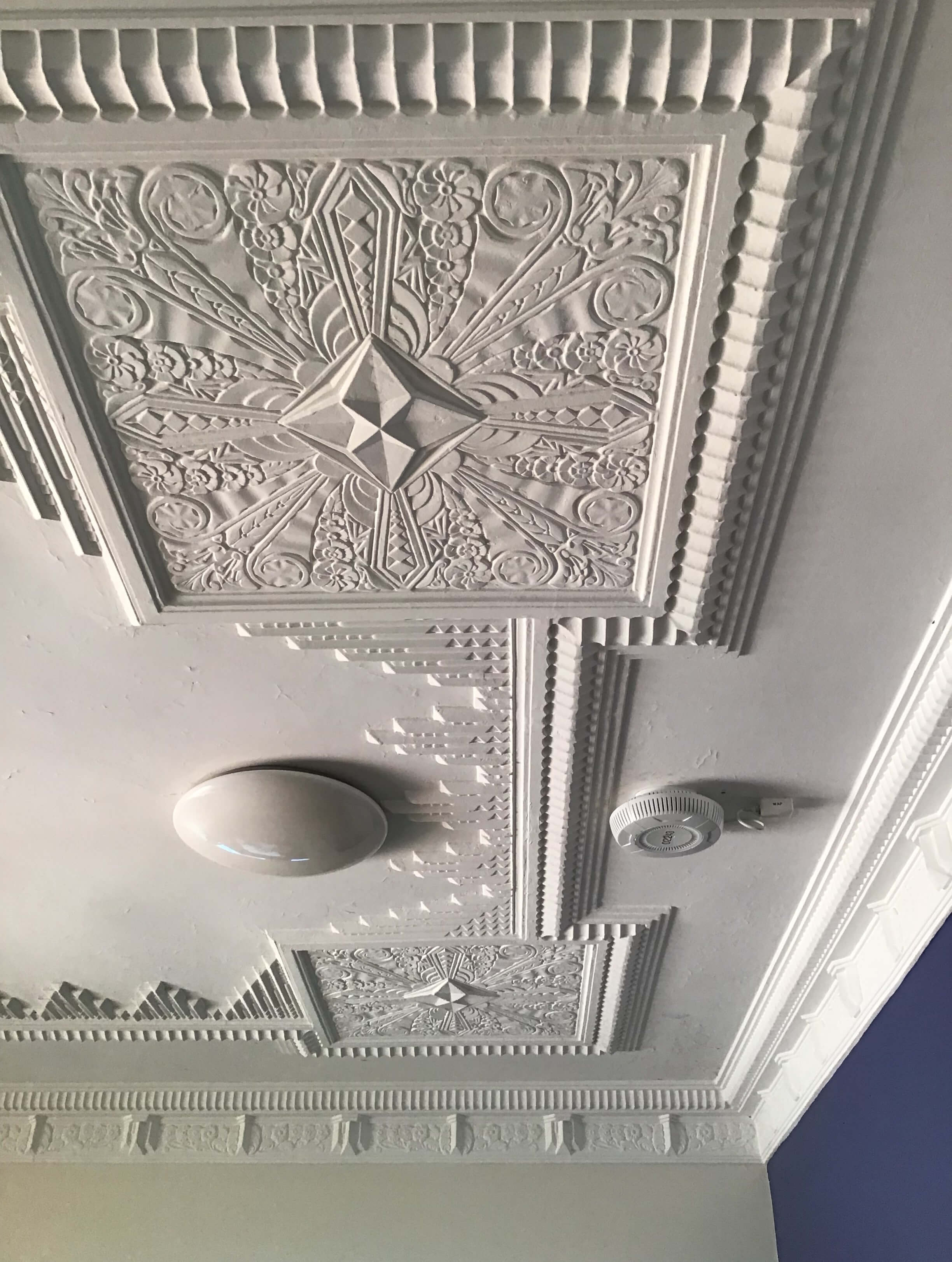 completed building maintenance in Brisbane view of detail of heritage-protected moulded plaster on white ceiling next to smoke detector and light fixture