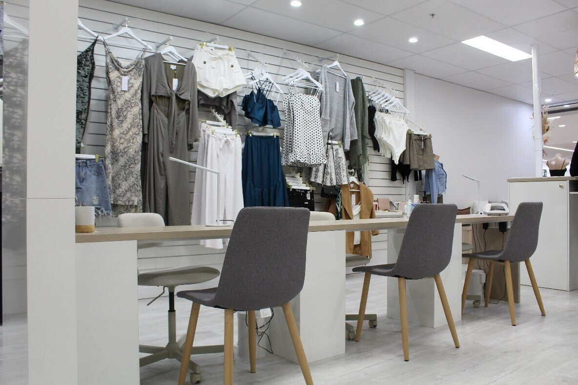 interior of retail nail bar after building fit out in Brisbane clothes displayed on walls grey and white manicure station with chairs and laminate floors