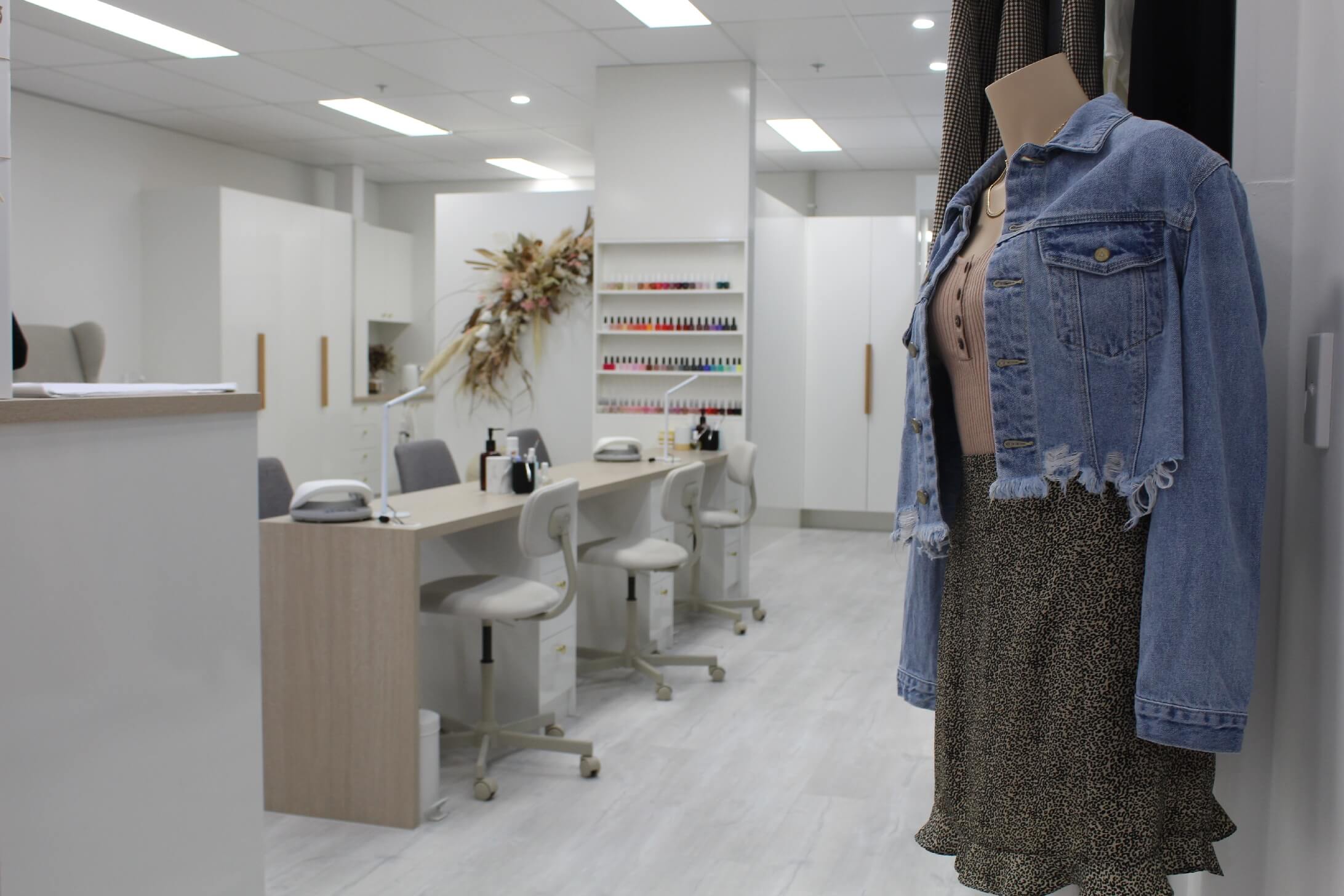 interior of nail bar after building fit out in Brisbane with mannequin in foreground and manicure stations in back white walls with gray accents 