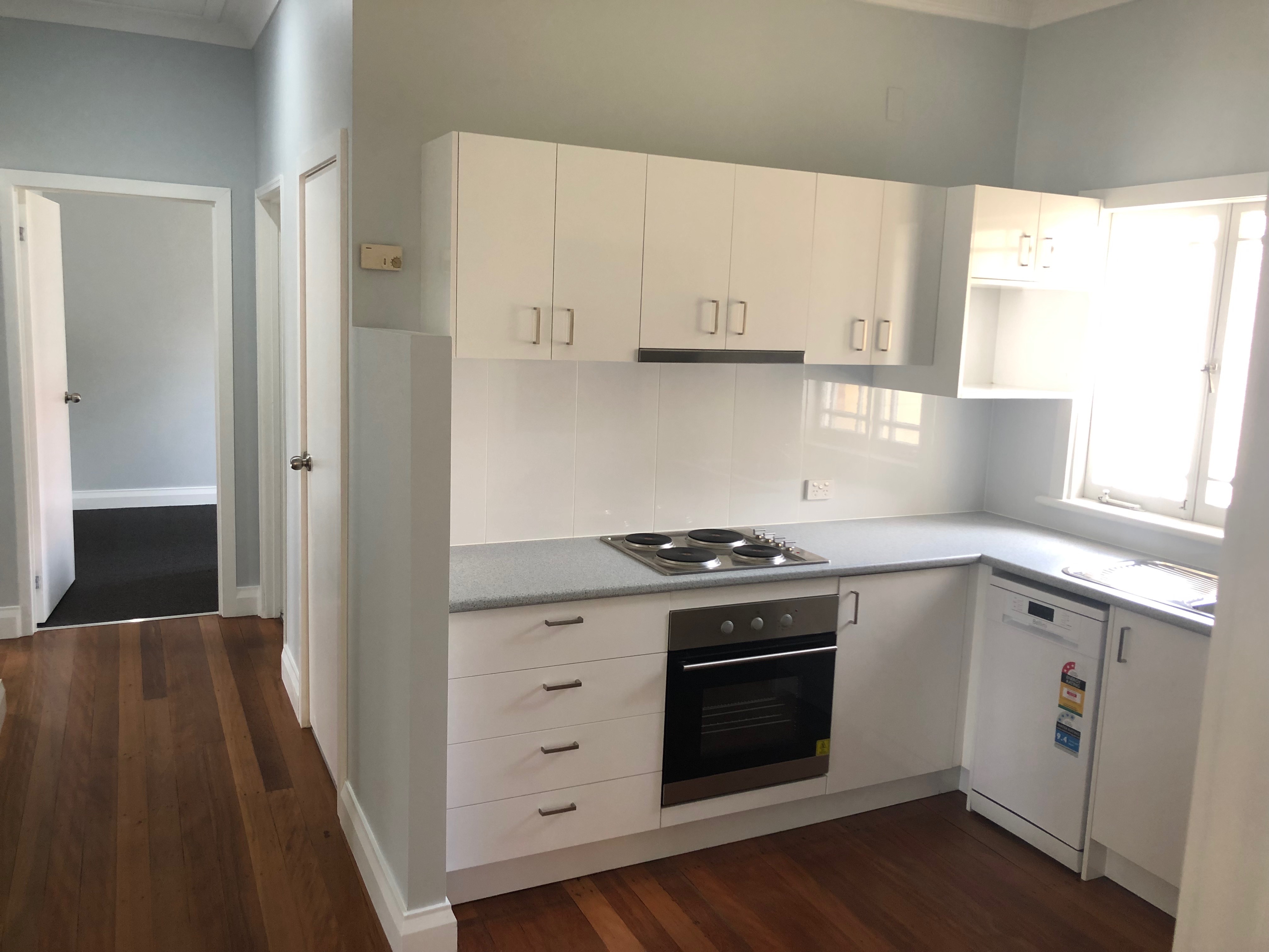 completed building maintenance in Brisbane view of newly refurbished kitchen in student boarding house white build in cupboards and oven laminate wood floors